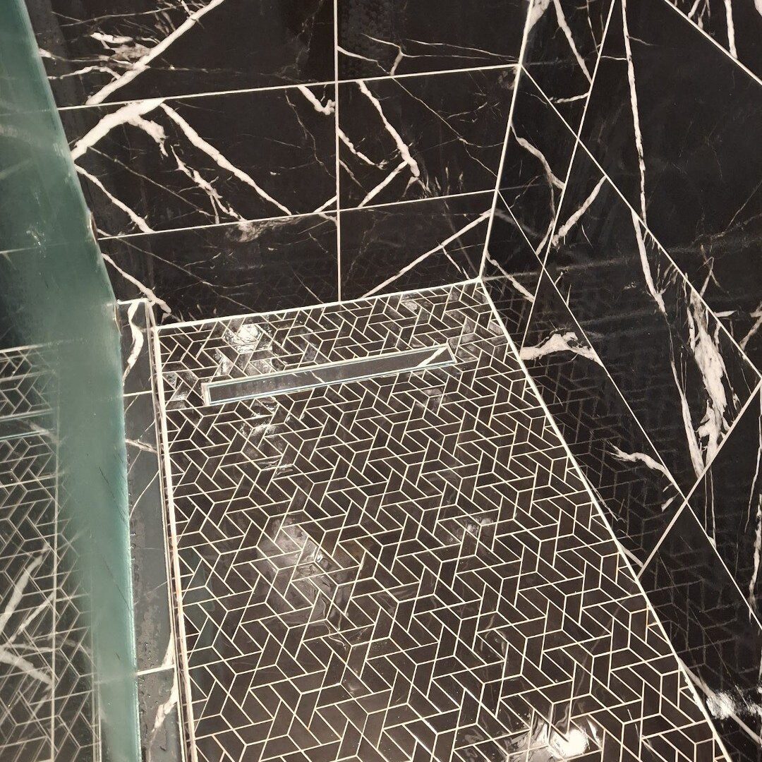 Black marble shower with geometric tile floor